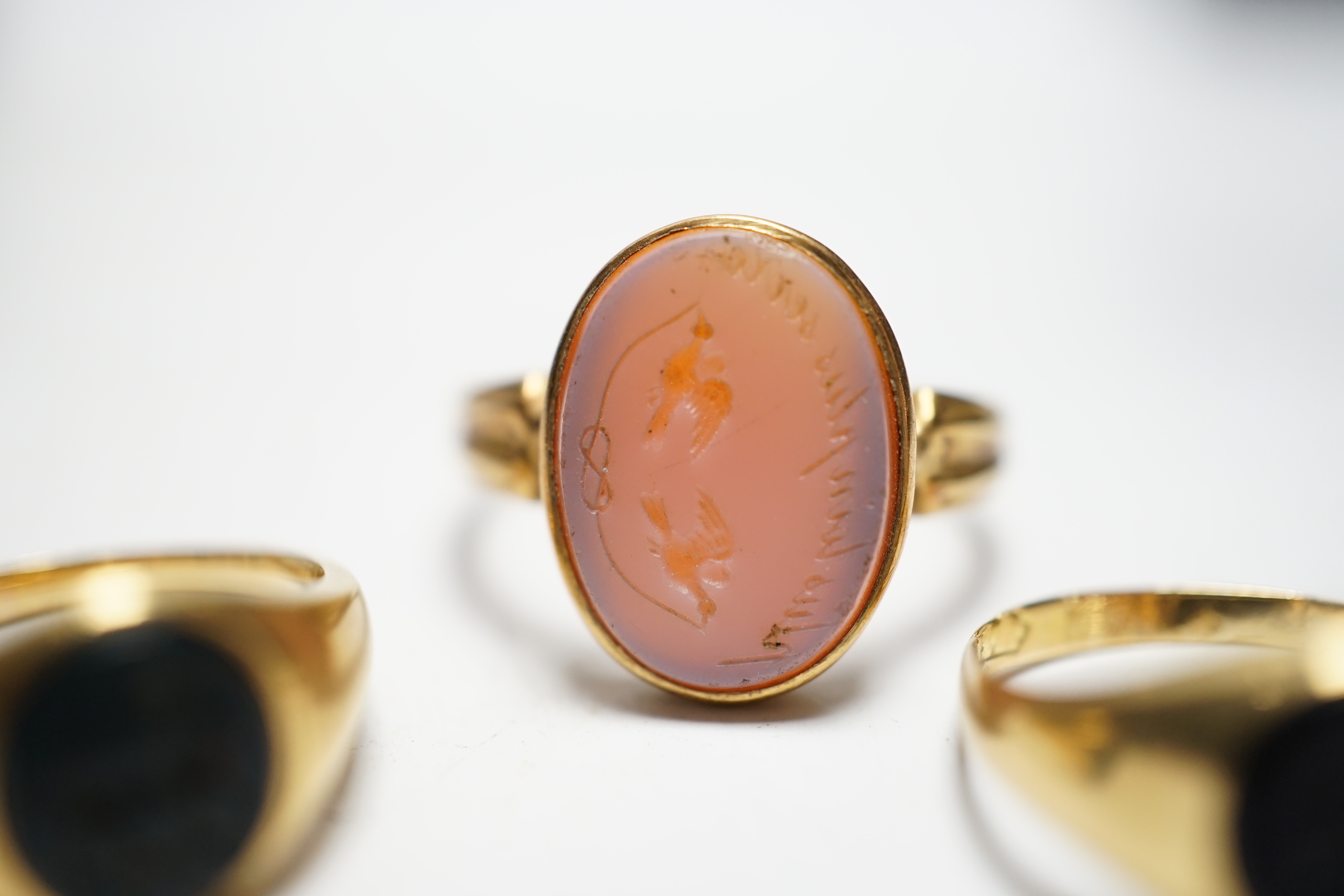 A Victorian yellow metal and sardonyx set oval seal ring, the matrix carved with two birds and motto, size O, together with two early 20th century yellow metal and chalcedony set child's signet rings, gross weight 9.7 gr